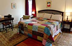 king bed with patchwork quilt, large desk, window