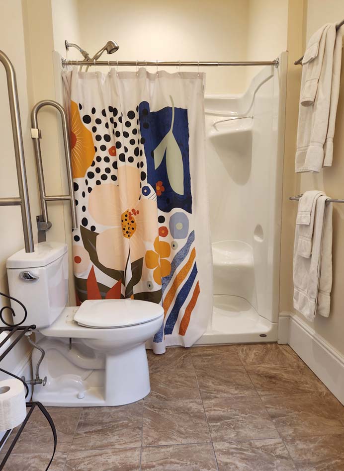 large bathroom with grab bars and shower seat