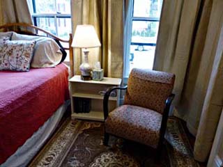 bed, upholtered chair, bookcase/nightstand, windows